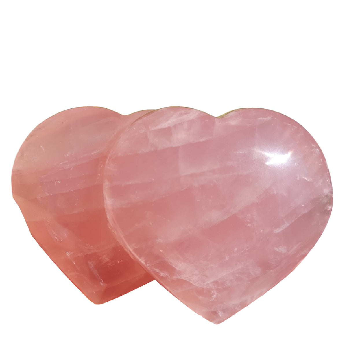 Two pink heart-shaped crystals held in hands with a blurred green background