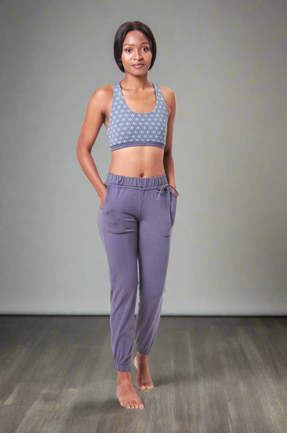 A woman standing, wearing gray knit pants with side pockets and a comfortable waist elastic.