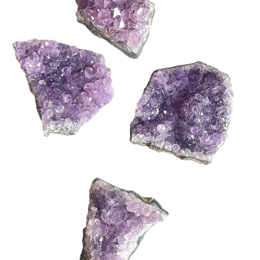 Several amethyst druses displayed on a marble surface, with their purple crystals visible.