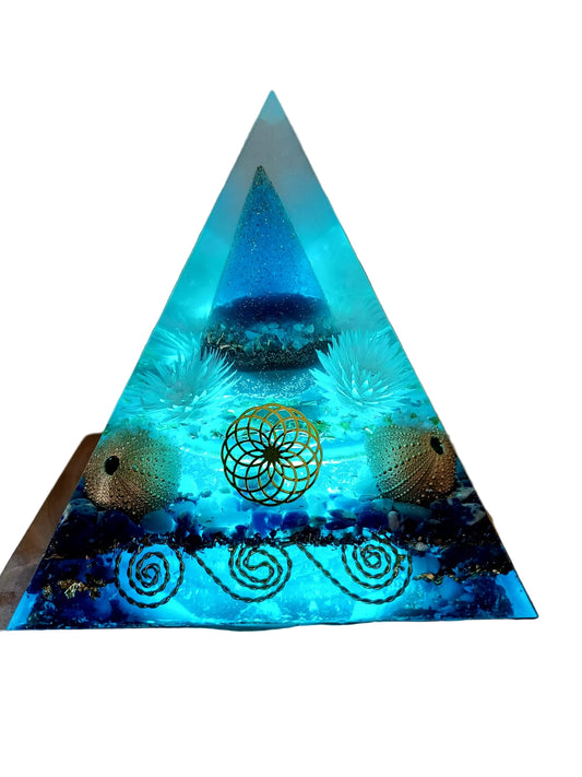 Triangular pyramid with a glowing blue interior and decorative elements on a wooden base.